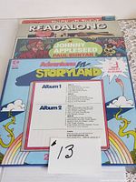 Four children's vinyl records stacked, top one Adventures in Storyland boxed set listing album track contents.