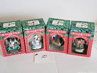 Four boxed vintage Ornamotion rotating Christmas ornaments set on a table. Boxes display red and green holiday graphics with clear windows revealing the ornaments inside.
