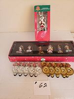 Overall view of vintage Disney Christmas ornaments including boxed Bugs Bunny stocking hanger and pack of silver and gold tone candle holder clips on white surface.