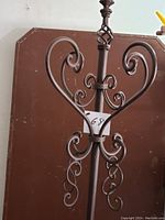 Close-up detail of the coat hanger's upper scrollwork decorative elements showing intricate curving and twisted metal design.