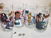 Photo showing set of four collectible Empire Strikes Back drinking glasses with colorful character illustrations and logos.