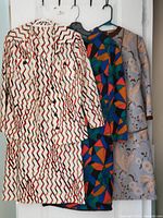 Front view of three dresses on hangers, showing colors and patterns
