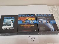 Lot of three sealed IMAX DVD box sets on a white surface: Into The Wild Collection, Galapagos, Blue Planet.