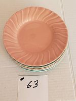 Stack of 6 ceramic plates, showing pink and light blue colors and swirl pattern on rim