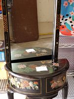 Tall demi-lune hall table with mirror showing black lacquer finish and colorful hand-painted floral and bird designs.