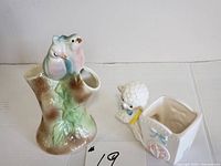 Full view of the bird-shaped ceramic planter and the smaller baby lamb planter side by side on a white surface.