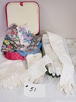 View of lot showing pink quilted holder with exposed handkerchiefs and two pairs of white gloves laid out on table.