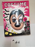 Photo of vintage child's Mickey Mouse mask visible through an oval window in original pink and white Halloween-themed box with bats, pumpkins, haunted house graphics.