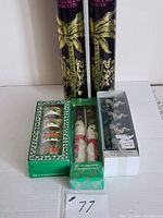 Two tall black and gold Fortnum & Mason biscuit tins, set of Christmas napkin rings, Santa Claus napkins, and silver-toned napkin rings in box arranged on white surface.