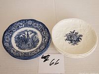 Photo showing one Liberty Blue historic colonial scene saucer with floral border and a stack of three Mason's Ascot on Oak saucers featuring a blue floral bouquet design.