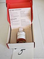 Perfume bottle in opened box with scent information leaflet inside box lid