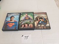 Five DVDs featuring Superman movies in special edition cases on a white table.
