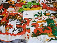 Five colorful vintage cotton terry half aprons featuring mushroom, floral, and vegetable prints laid out together with a label showing '21'.