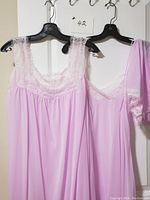 Full view of lilac nylon nightgown and slip on hangers with matching panty held on the side. Detail of lace around neckline, straps, and hem visible.