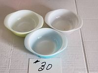 Three vintage Pyrex small bowls in pastel yellow, blue, and gray, top view showing interior.
