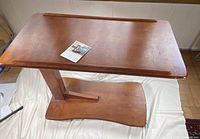 Top angled view of the wooden adjustable height side table showing the tabletop with raised edges and smooth wood finish.