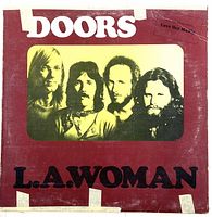Front cover of The Doors 'L.A. Woman' vinyl record featuring band photo and album title.