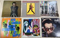 Six Elvis Costello vinyl record album covers laid out, showing different album artworks.