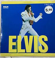 Front cover of Elvis Presley double album vinyl record set with price sticker indicating $5.98. Shows Elvis in white jumpsuit performing against a blue background with large yellow text 'ELVIS'.