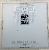 Front cover of 'The Friends of Mr. Cairo' vinyl album by Jon and Vangelis showing minimalist black line art design on white background with portraits and album title.