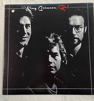 Front cover of King Crimson Red vinyl record album showing black and white image of band members with title text.