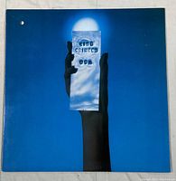 Front cover of King Crimson USA vinyl record, showing blue background with hand holding reflective object with title.