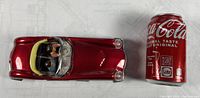 Top-down view of retro red tin pull car next to a Coca-Cola can for size comparison.