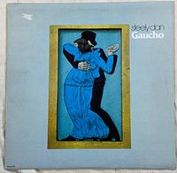 Front cover of the vinyl record 'Gaucho' by Steely Dan, featuring a painted dancing couple in black and blue on a light blue background with some wear and a small tear on the upper left corner.