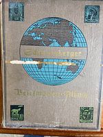 Brown Schweizer Briefmarken-Album front with four affixed vintage stamps from USA, Norway.