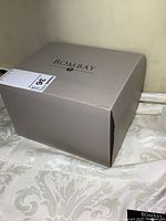 Closed Bombay jewelry box in grey box with label and branding on top.