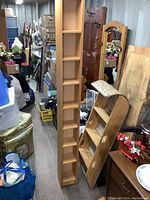 Full view of the tall CD/DVD tower with adjustable shelves placed among other furniture and items.