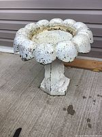 View of the bird bath showing scalloped edge basin with paint chipping and surface pitting.
