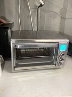 Front view of the stainless steel convection oven showing digital display, control knobs, and glass door with rack inside.