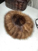 Top view of a round vintage ladies fur hat showing dense brown fur with darker patch in center.
