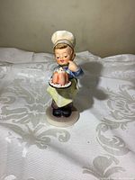 Front view of the Goebel Hummel porcelain figurine showing the child in chef attire holding a dessert plate with a bundt cake.