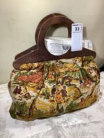Front view of vintage knitting bag showing fabric with rural scene pattern and wooden handles