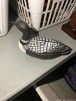 Side view of a 12-inch hand painted ceramic loon figurine with detailed black and white feather patterns and red eyes.