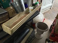 49-inch long wood planter box on stand with metal bucket and plant food nearby