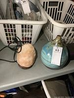 Salt lamp next to blue pottery vase on shelf with laundry baskets in the background