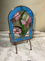 Front view of stained glass panel with pink butterflies and flowers on metal stand