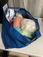 Large blue bag containing several mixed balls of yarn in various colors and knitting pattern books.