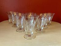 Eight vintage WJ Hughes etched glasses arranged on table, showing full set with floral corn flower design.