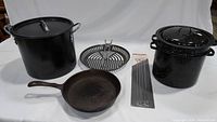 Front view photo showing all cookware items arranged including stock pot, grill pan, skewers, double boiler, and cast iron fry pan.