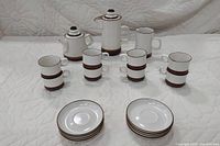 Full view of the 4-piece tea set including teapot, sugar bowl, creamer, four cups stacked, and four saucers stacked on a white background.
