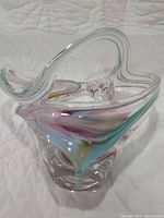 Front and side view of vintage hand blown art glass sculpture with pink, light blue, and light yellow swirls inside clear glass, showing its abstract curved shape.
