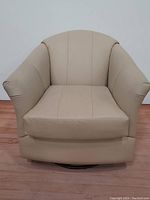 Front overhead view showing the beige leather upholstery and chair shape, including armrests and seat design.