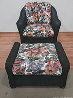 Full view of green wicker chair and ottoman with floral cushions on a wood floor.
