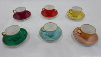 Six colorful Richard Ginori tea cups with saucers nicely arranged, showing each item's color and gold rim details.