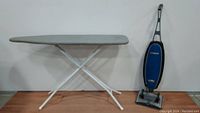 Full view of the ironing board and Oreck vacuum cleaner standing upright.
