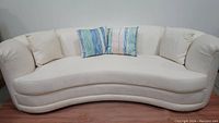 Front view of white curved sofa with cushions, showing sea/ocean patterned fabric close-up.